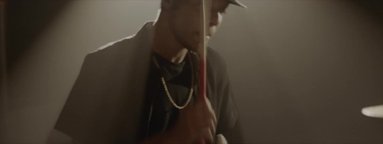 Black man wearing black hat plays drums at stage