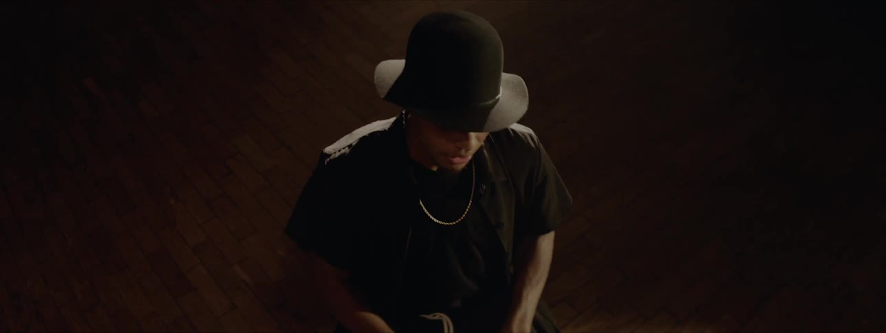Black drummer wearing black hat plays drums at the stage