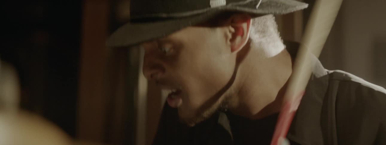 A young black man in a hat is focused intently as he keeps time while vigorously playing the drums