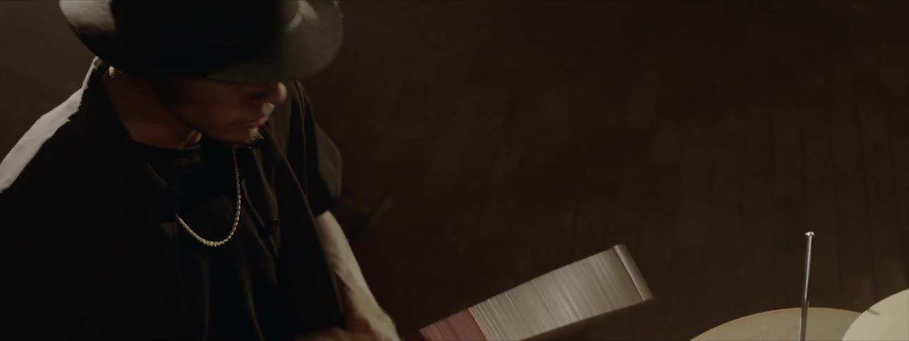 A man plays the drums while bobbing his head to the music