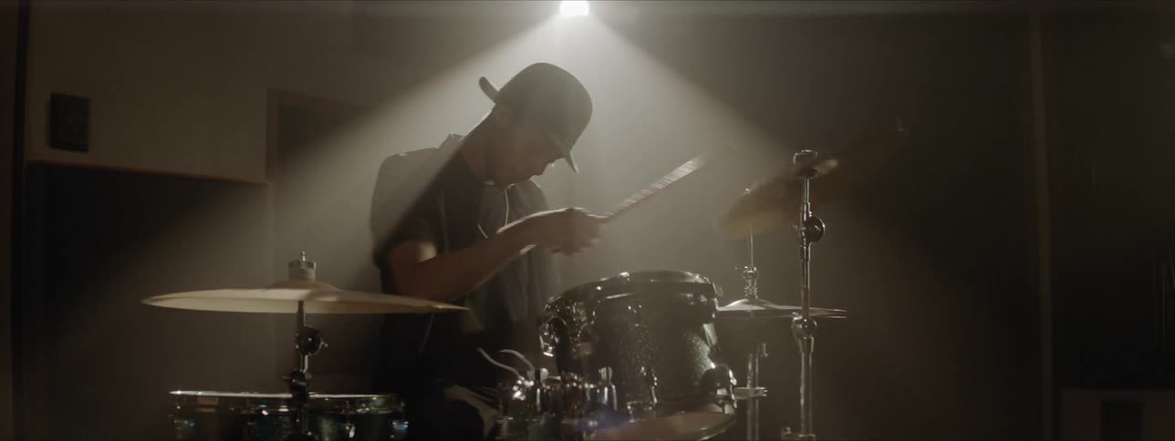 A young black man plays the drums