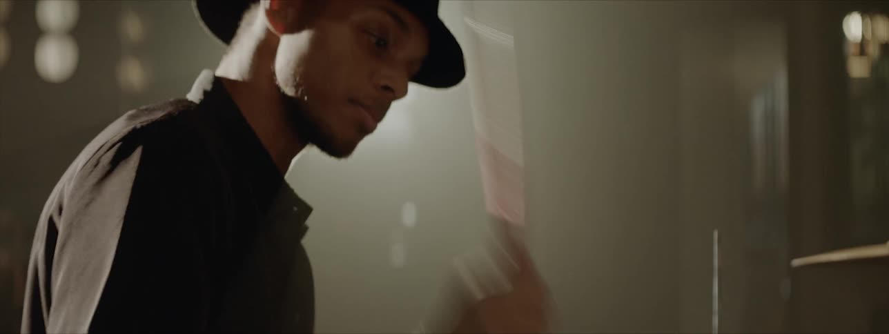 Black drummer wearing black hat plays drums at the stage