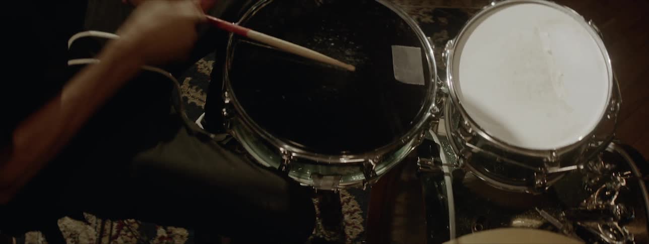 Black drummer wearing black hat plays drums at the stage