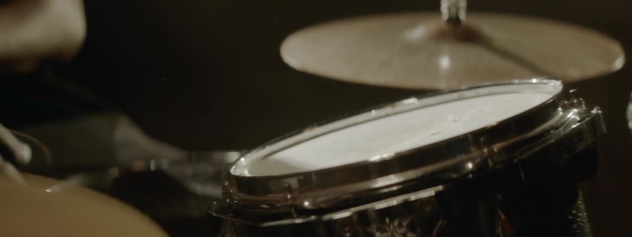 A person plays on a drum set