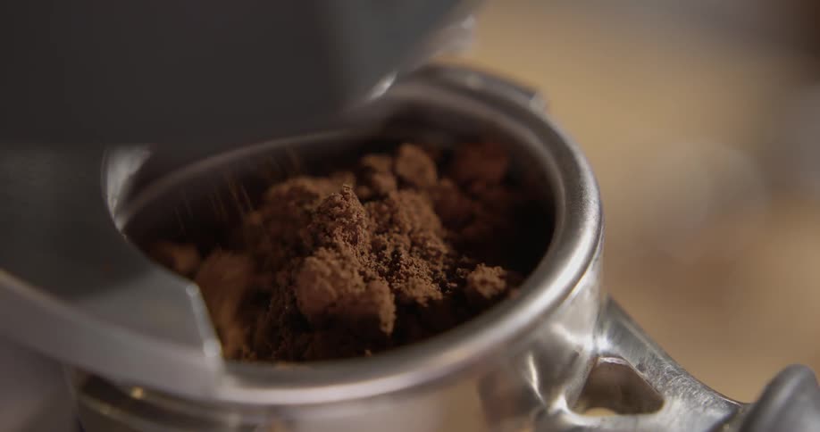 A person filles the coffee machine up with grounds