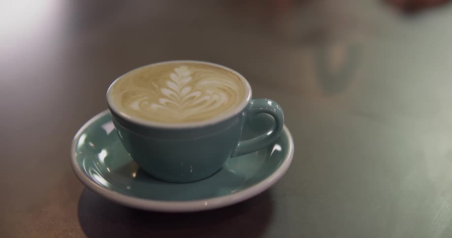 A latte with a design on top sits on a counter