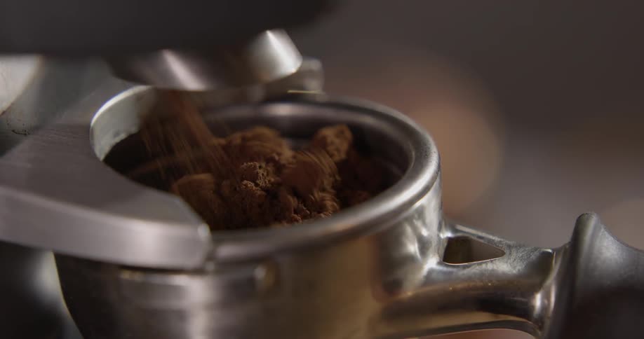 A machine dispensing coffee grinds into a metal container