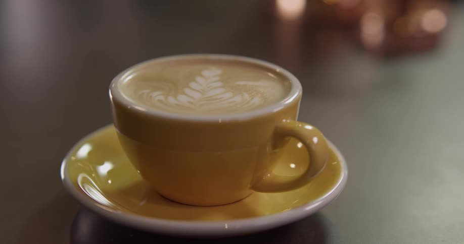 A person sets down a coffee cup and saucer and then picks it up again