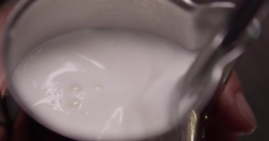 A person fills a cup with a foamy liquid