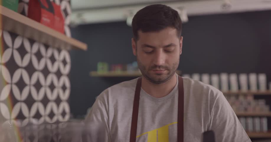 A man in a restaurant concentrates as he makes a coffee