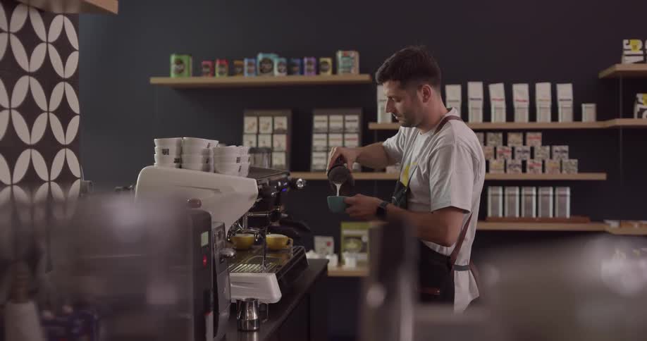 Barista pours coffee and milk into a mug