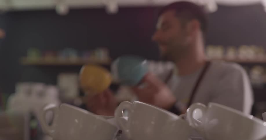 A man picks up two mugs from a stack
