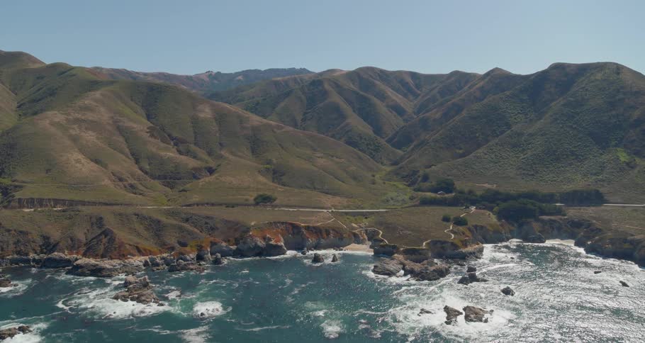 A rocky coast with a road and hills in the background