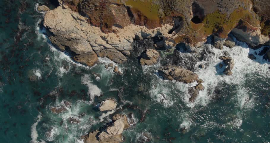 Birds eye view of rocky coast with waves crashing on rocks