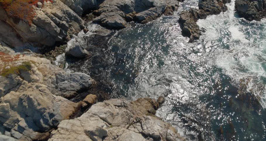 Waves crash and move between rocks on a coastline