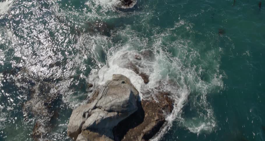 Several rock formation can be seen from above as the ocean wave crash against them along a rocky coastline
