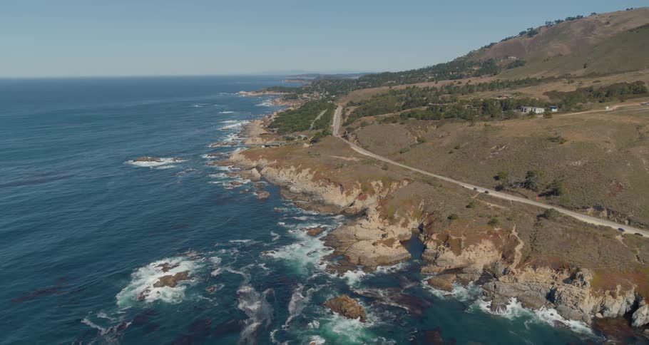 A lengthy road runs alongside the ocean that meets up with a gently sloping coastline