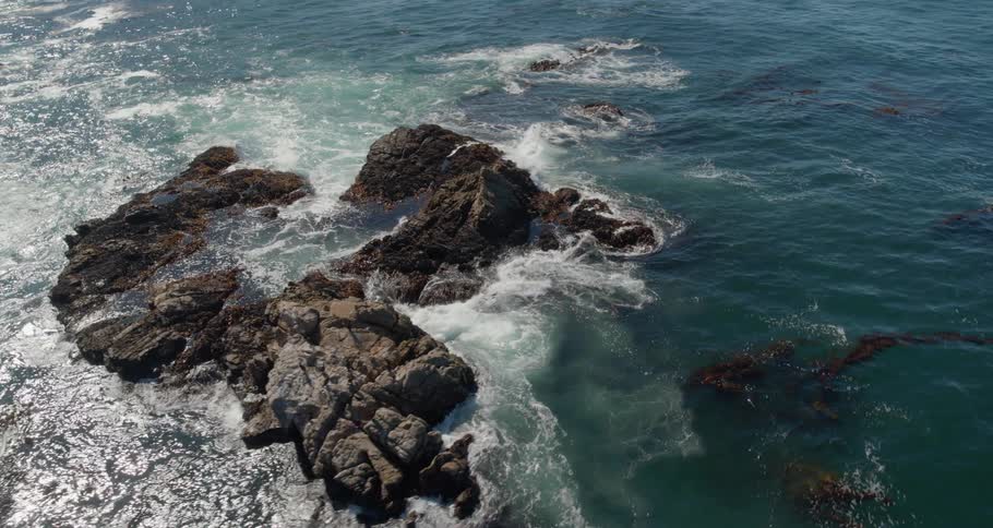 Ocean waves splash and break against the rocks off shore
