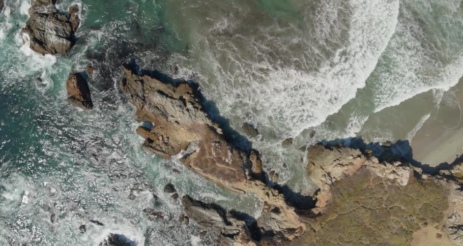 Waves crashing on cliffs and a sandy beach