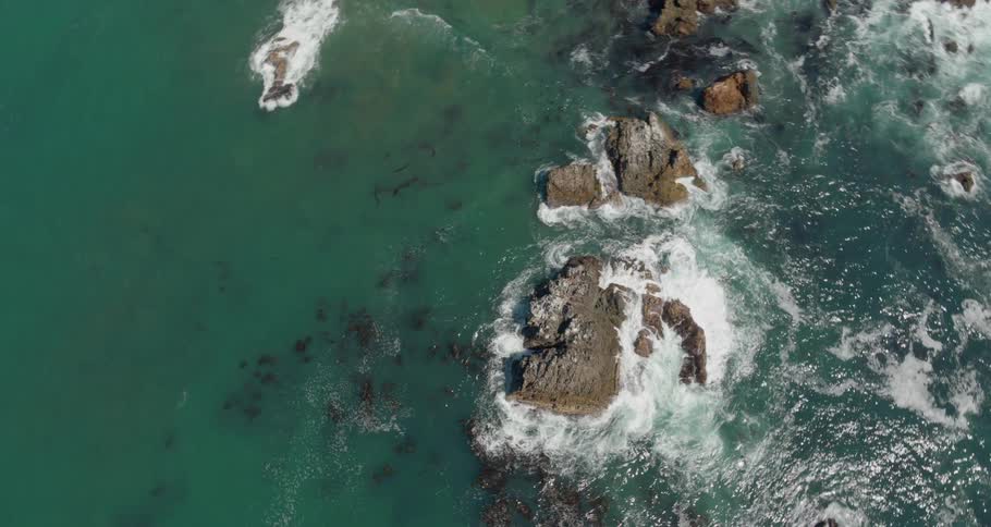 Waves crash along large rocks in the ocean and coast line