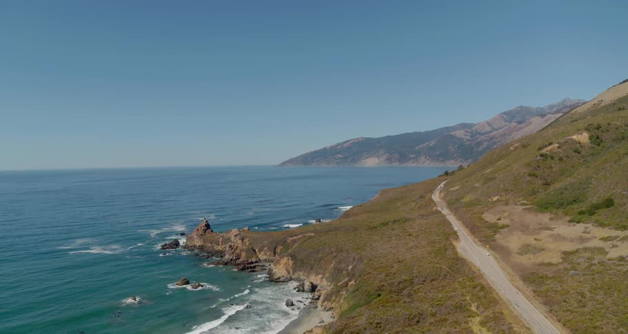 A scenery of a beautiful ocean near the road and hills