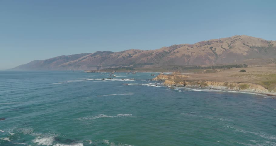 A beach with a rocky shore with mountains in the background