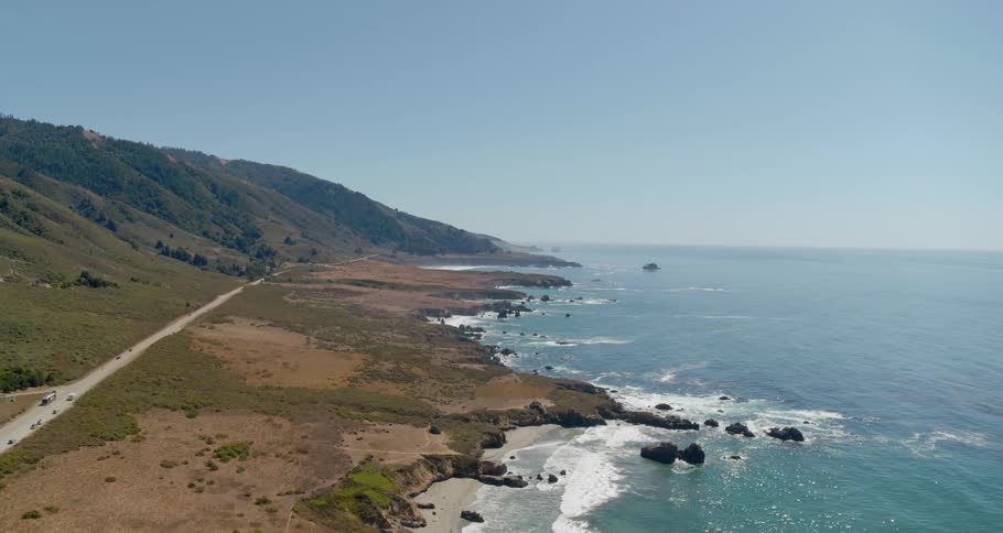 A road along a hilly coastline during the day