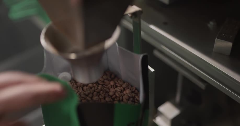 Someone places empty bags under a spout to be filled with coffee beans
