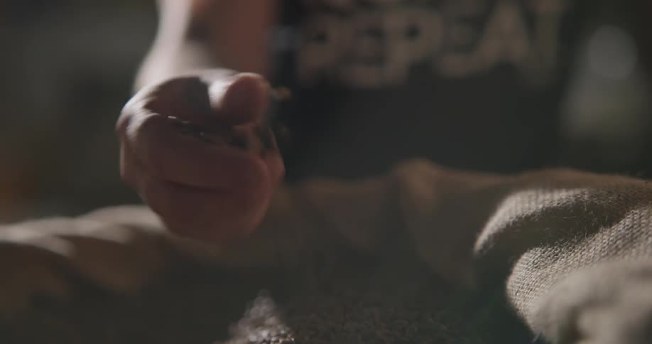 A person picks up a handful of coffee beans and runs it through their fingers