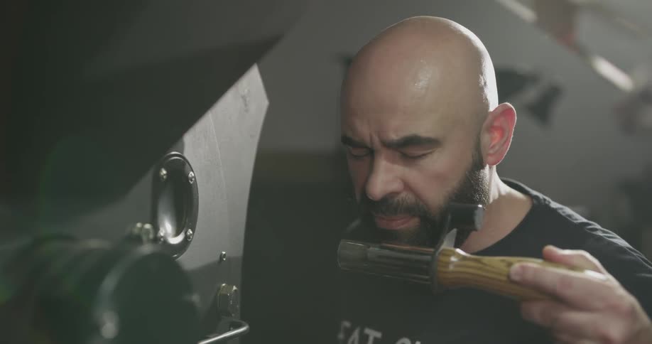 A man spins and removes something from a large machine to smell it