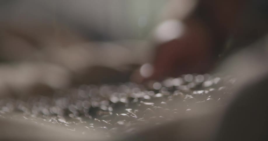 A person scooping coffee beans with their hands and letting the beans spill through their fingers