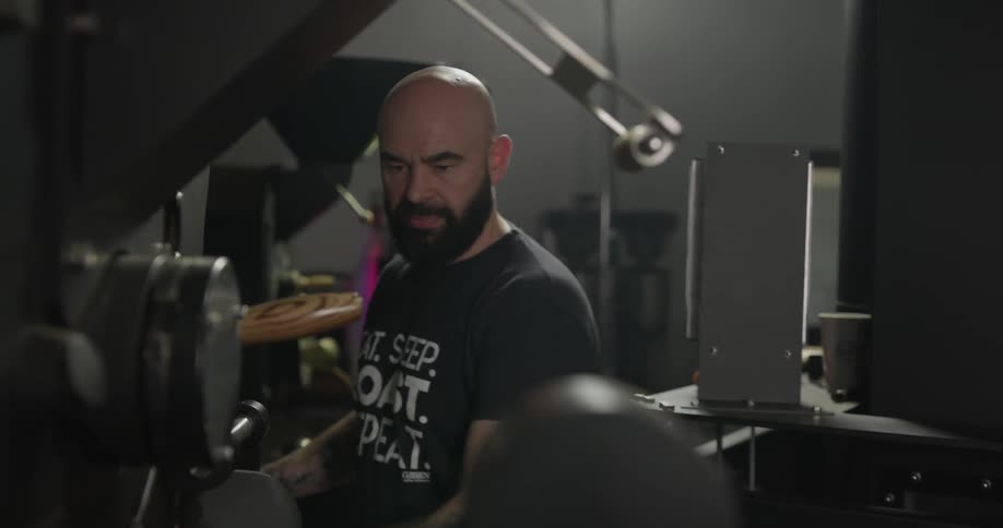 A man sampling the coffee roasting in a vat by smell