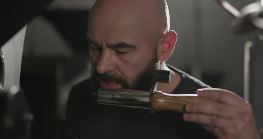 A man removing and blowing on a part from a machine before replacing it