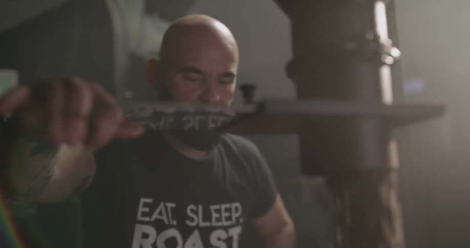 A man uses a machine to pour coffee beans