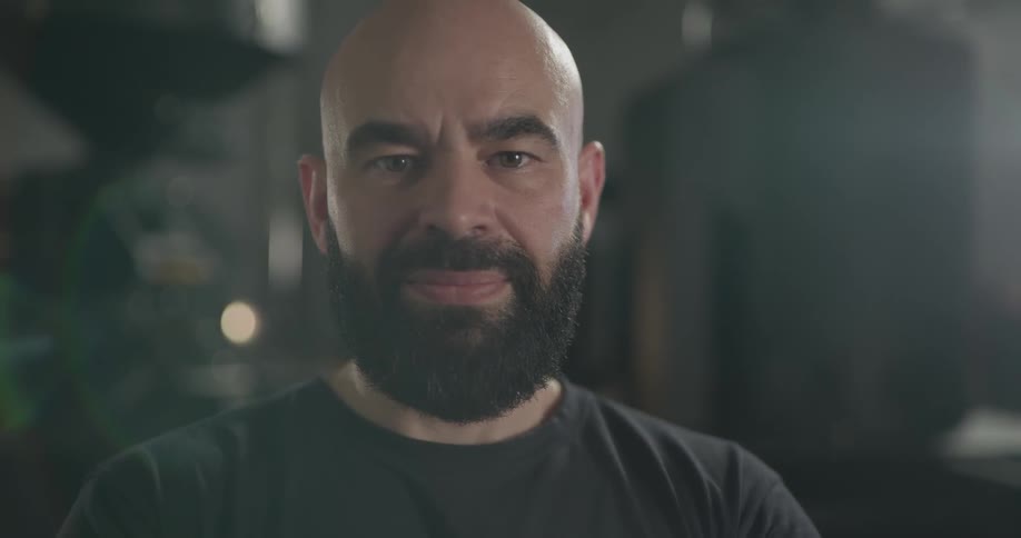 Bald bearded man looks at the camera and smiles indoors during daylight