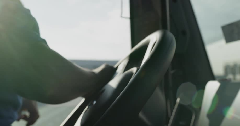 Truck driver turns the steering wheel in his truck cab