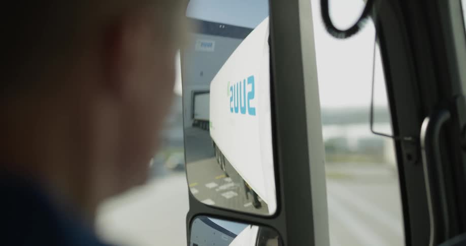Truck driver checks the mirror and drives on a sunny day