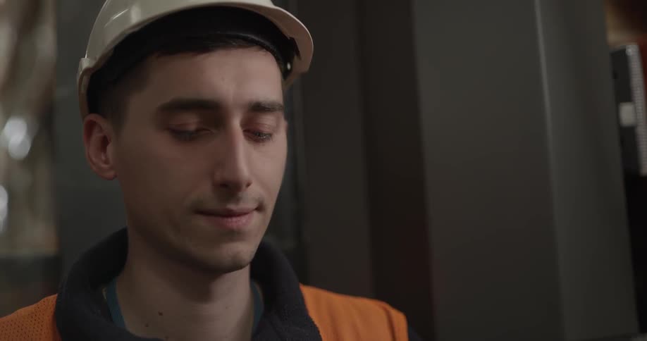 A young man in a hard hat looks around