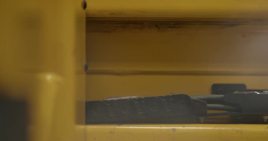 A group of wire are positioned withing a bendable protective harness that is attached to a machine that is moving back and forth