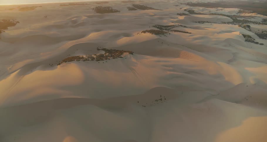 Sand dunes cover a desert landscape