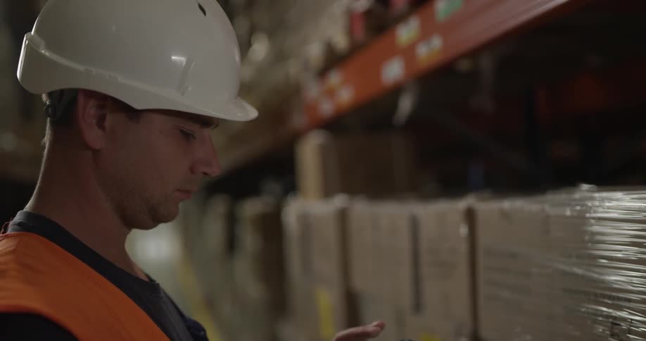 A man scans a label on a shelf in a warehouse