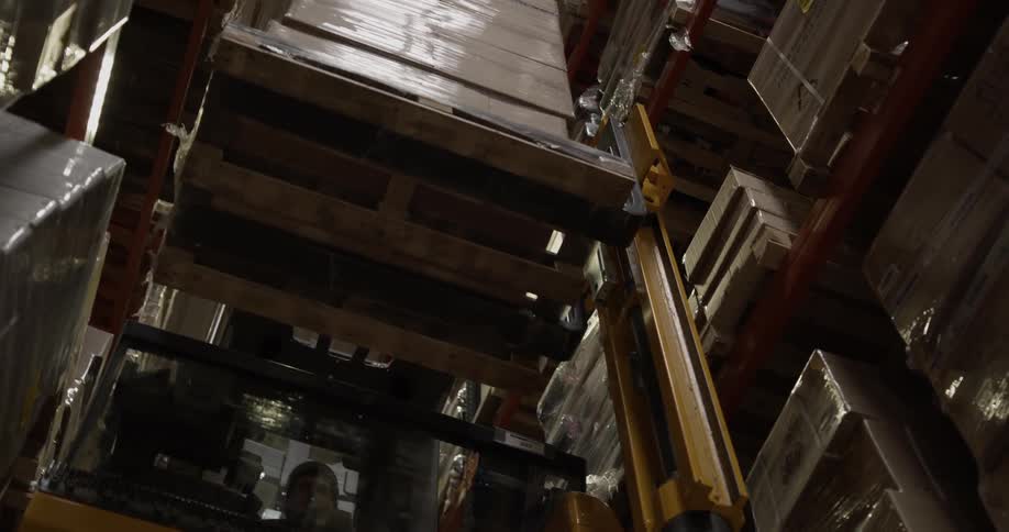 A forklift removes boxes from a warehouse shelf