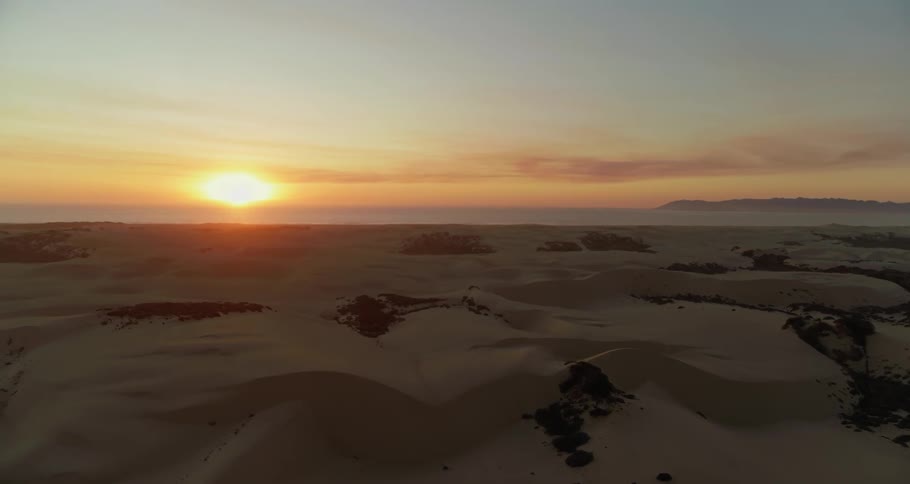 Aerial view of sand dunes and ocean at sunset