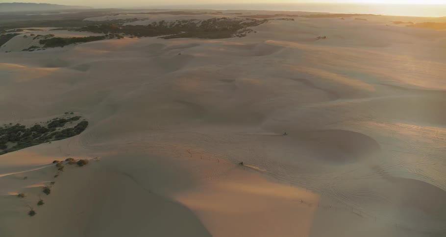 Motorcycles driving on desert sand dunes at dusk