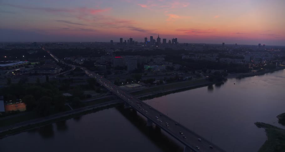 Aerial view of waterfront city and bridge over river at sunset