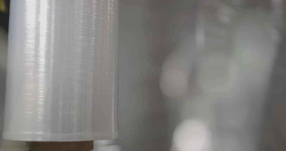 A machine spinning a large box to wrap it in a plastic film