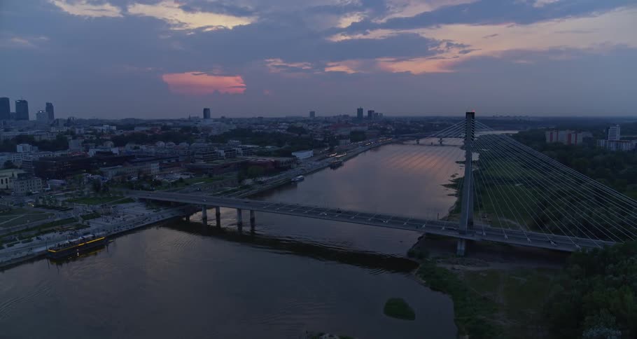 Suspension bridge over river on waterfront city at dusk