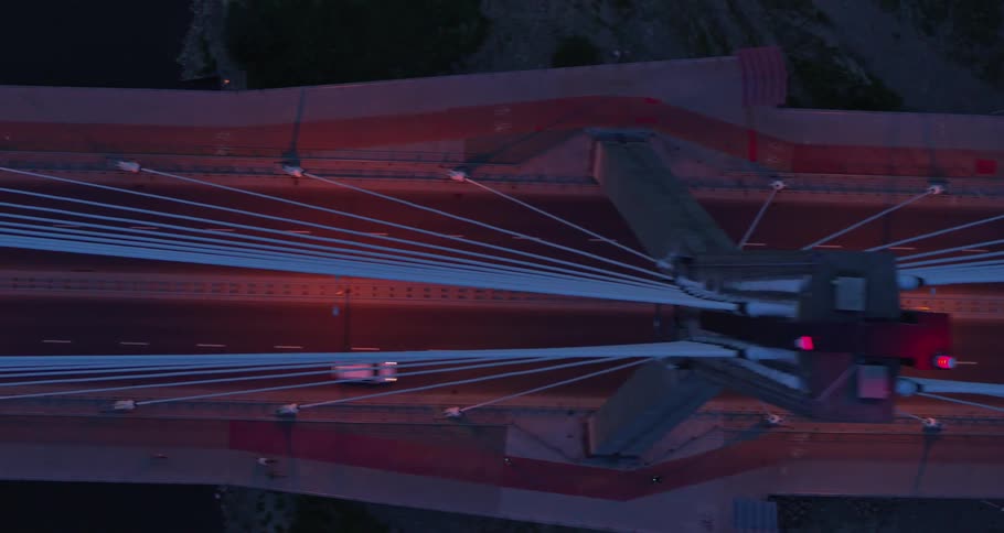 People ride bicycles and drive cars over the bridge at night