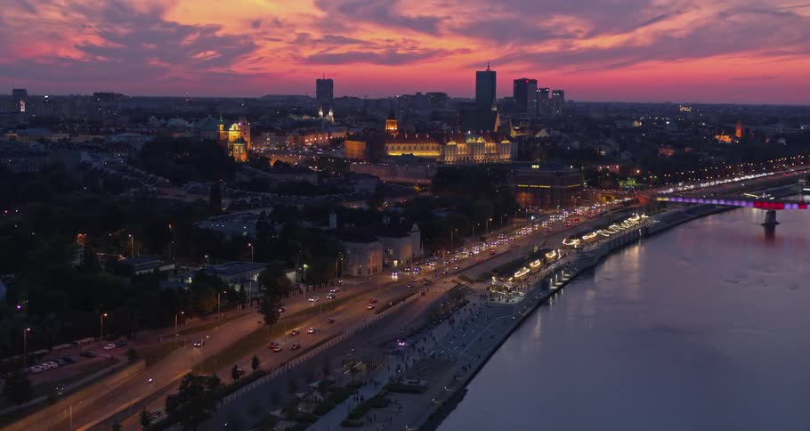 Skyline of the illuminated city with cars driving on the road at sunset