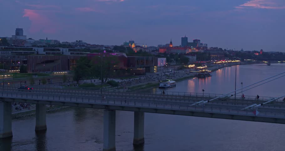 People and cars travel over the bridge at sunset